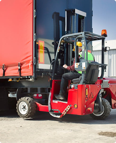 Man driving skidsteer grabbing items from semi
